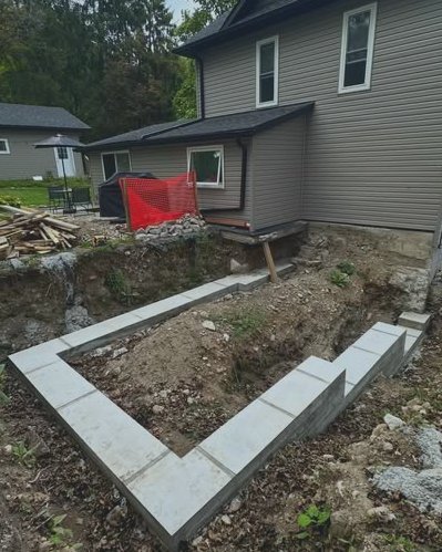 Concrete footings excavated beside a gray vinyl siding home in Wilson, NC