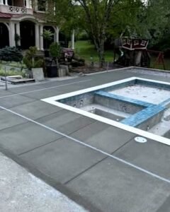 Concrete pool deck with saw cuts around a blue tiled spa in Wilson, NC