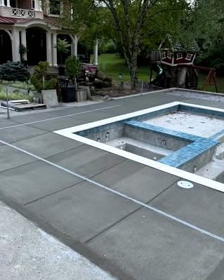 Concrete pool deck with saw cuts around a blue tiled spa in Wilson, NC
