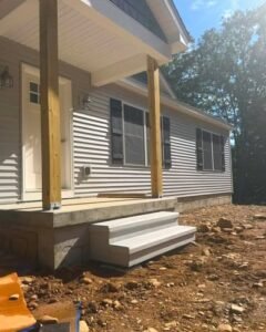 Concrete porch with gray steps and wood posts on a vinyl siding home in Wilson, NC