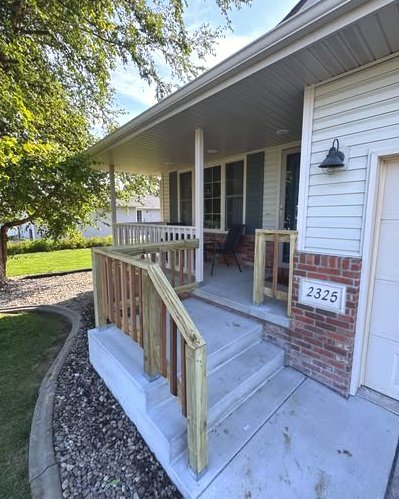 Concrete porch with new wood railings, brick, and steps in Wilson, NC
