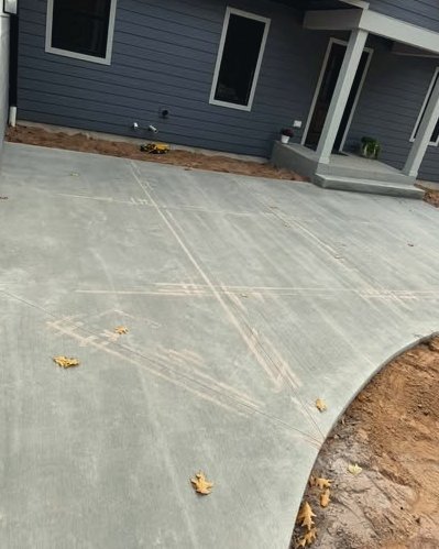 Fresh gray concrete patio beside a dark siding home with a curved edge in Wilson, NC
