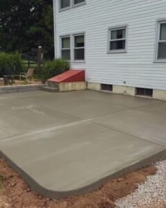 Fresh gray concrete patio with a rounded corner beside a white house in Wilson, NC