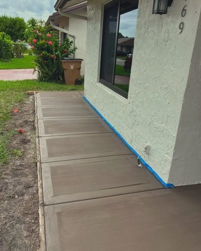 Fresh concrete sidewalk with blue tape beside a stucco home in Wilson, NC