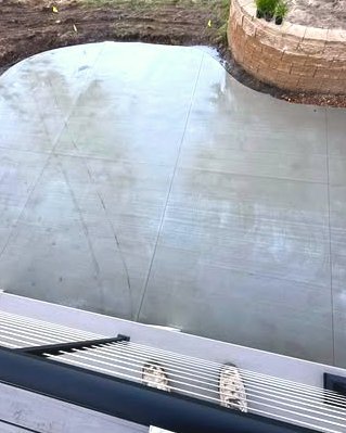 Curved concrete patio pour beside a stone block wall in Wilson, NC