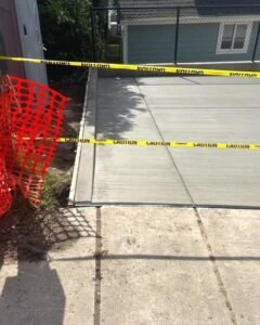 New concrete driveway apron with caution tape beside a garage in Wilson, NC