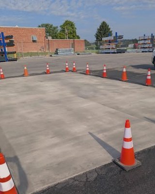 Concrete parking lot pour with orange cones beside a brick building in Wilson, NC