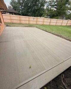New broom finished concrete patio beside a brick home with a fence in Wilson, NC