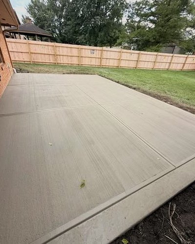 New broom finished concrete patio beside a brick home with a fence in Wilson, NC